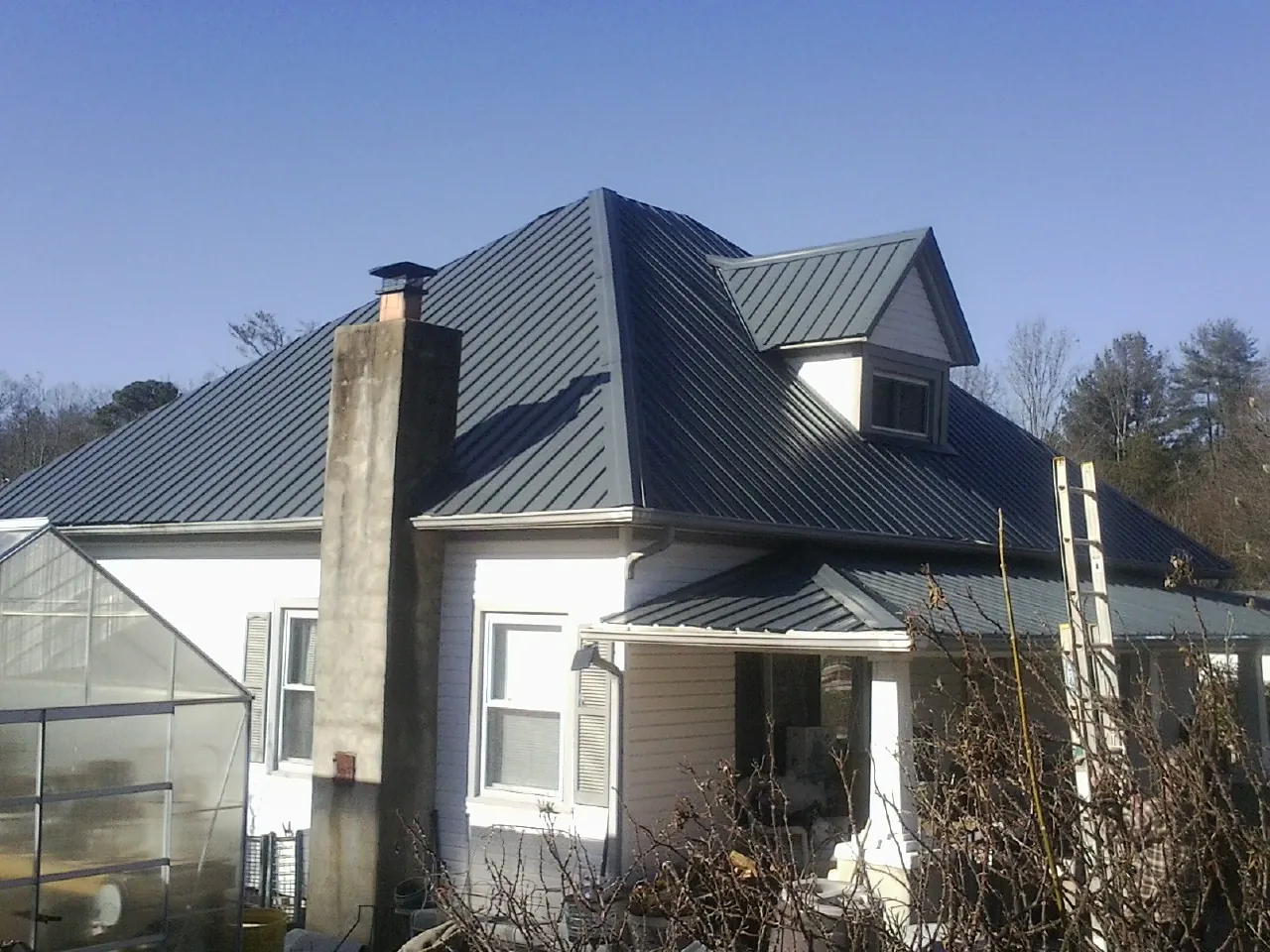 Dark blue standing seam metal roof on a white farmhouse with dormer — Slate & Tile Roof Repair by Roofing Brothers in Duncansville