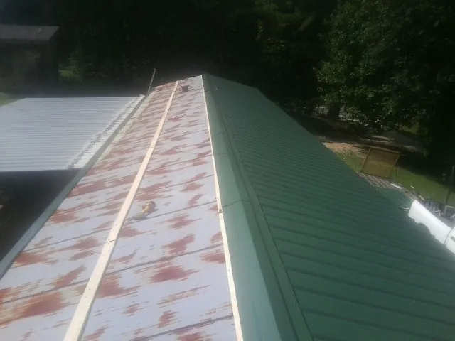 Old rusted panels beside newly installed green metal roofing — Wind Damage Roof Repair by Roofing Brothers in Duncansville