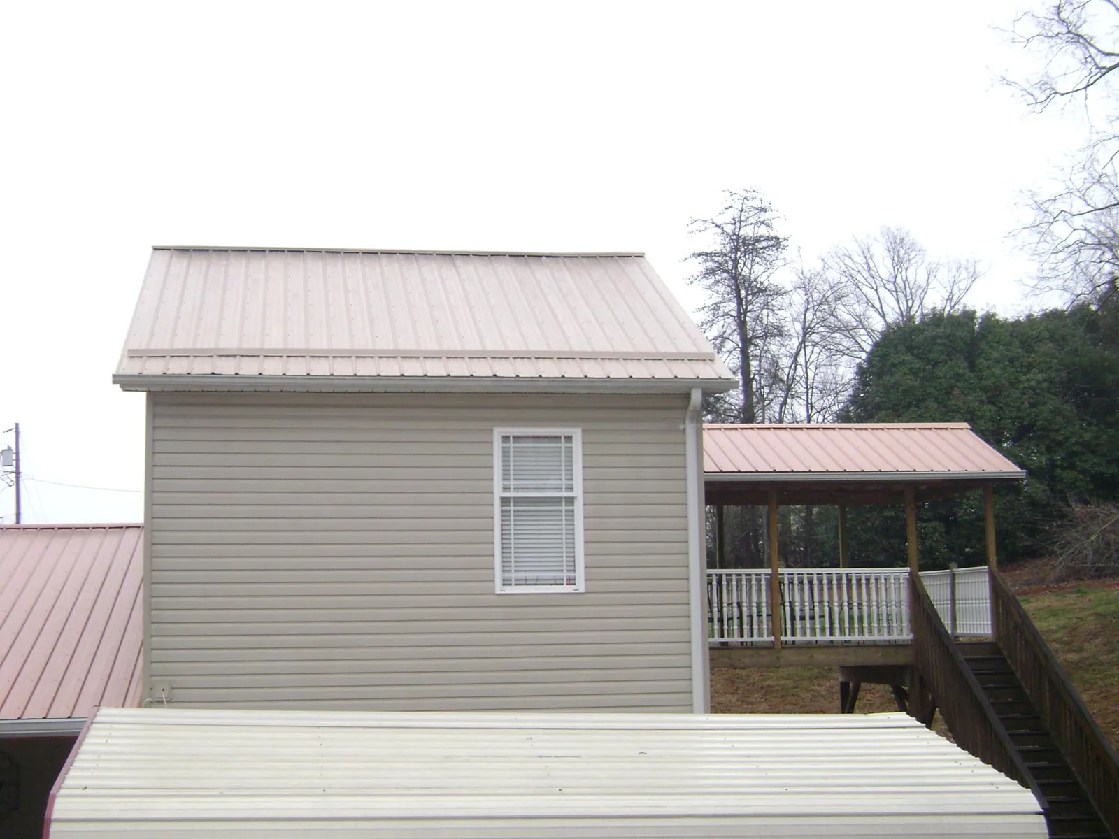 Tan metal roofs on a two story addition and attached porch, from a Roof Replacement job in Duncansville