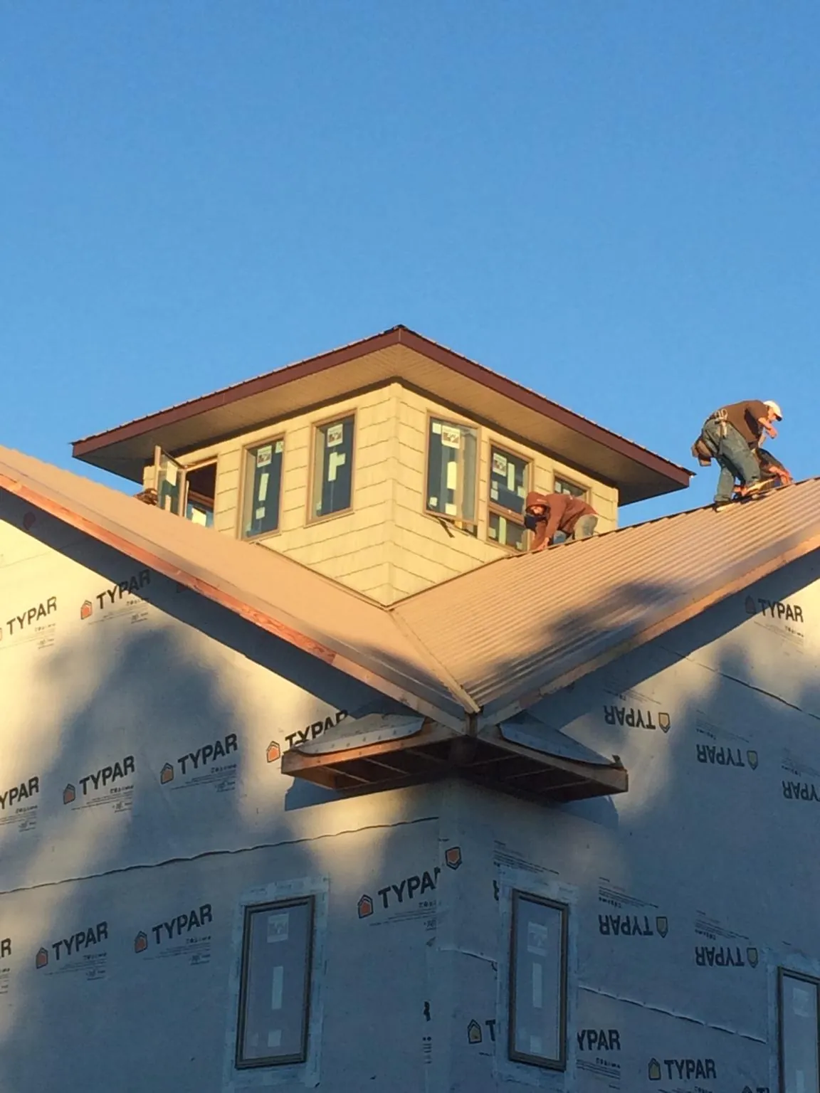 Roofers working around a rooftop cupola on a new metal roof at sunset — Roof Waterproofing in Duncansville by Roofing Brothers